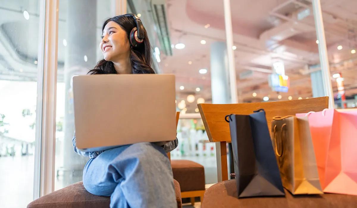 Woman on laptop looking out the window at a shopping mall