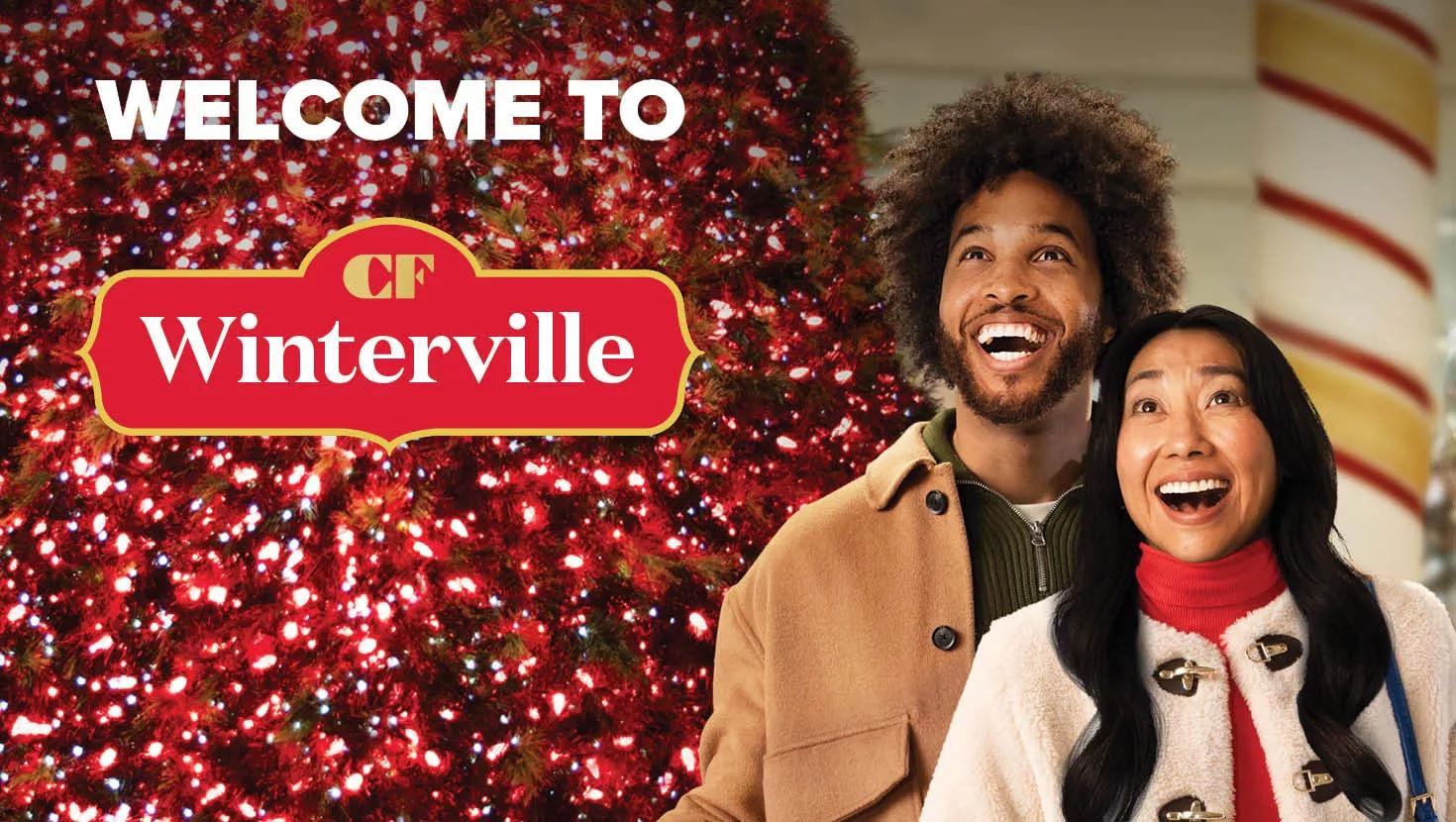 Two people smiling and looking upward in awe, standing in front of a brightly lit Christmas tree with red and white lights. The text 'WELCOME TO CF Winterville' appears above them, with the CF Winterville logo in red and gold. 