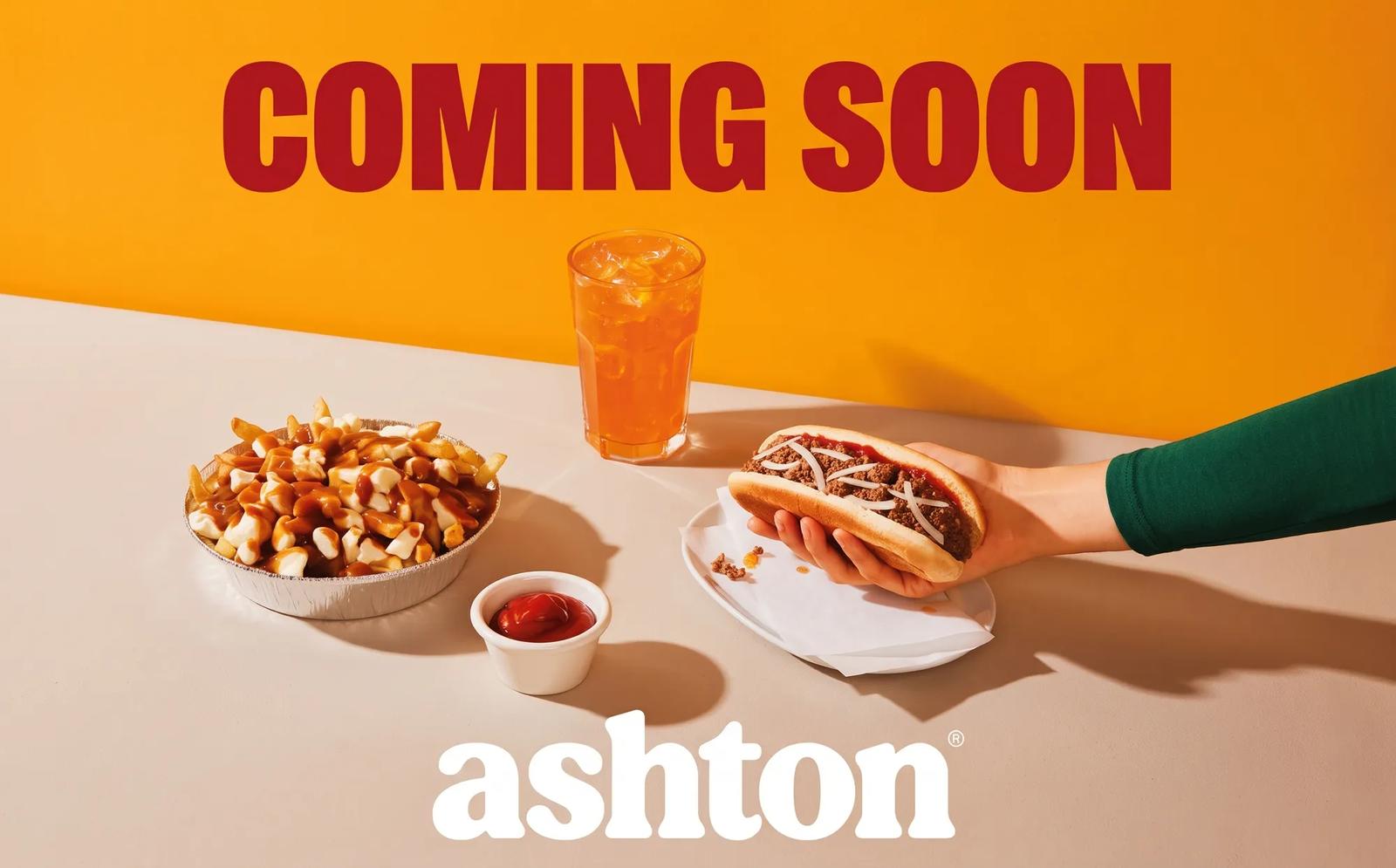 An Ashton ad reading "Coming Soon" featuring a hand holding a hot dog next to a bowl of poutine and an iced drink.