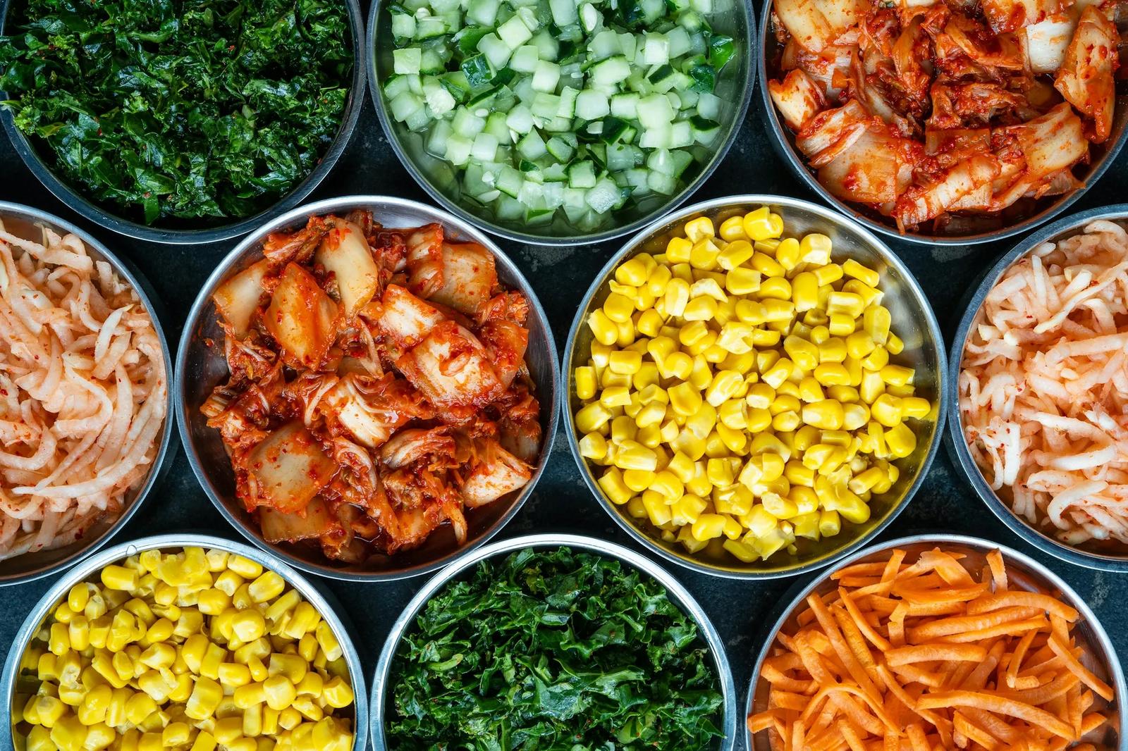 An overhead view of small metal bowls filled with assorted colorful ingredients.
