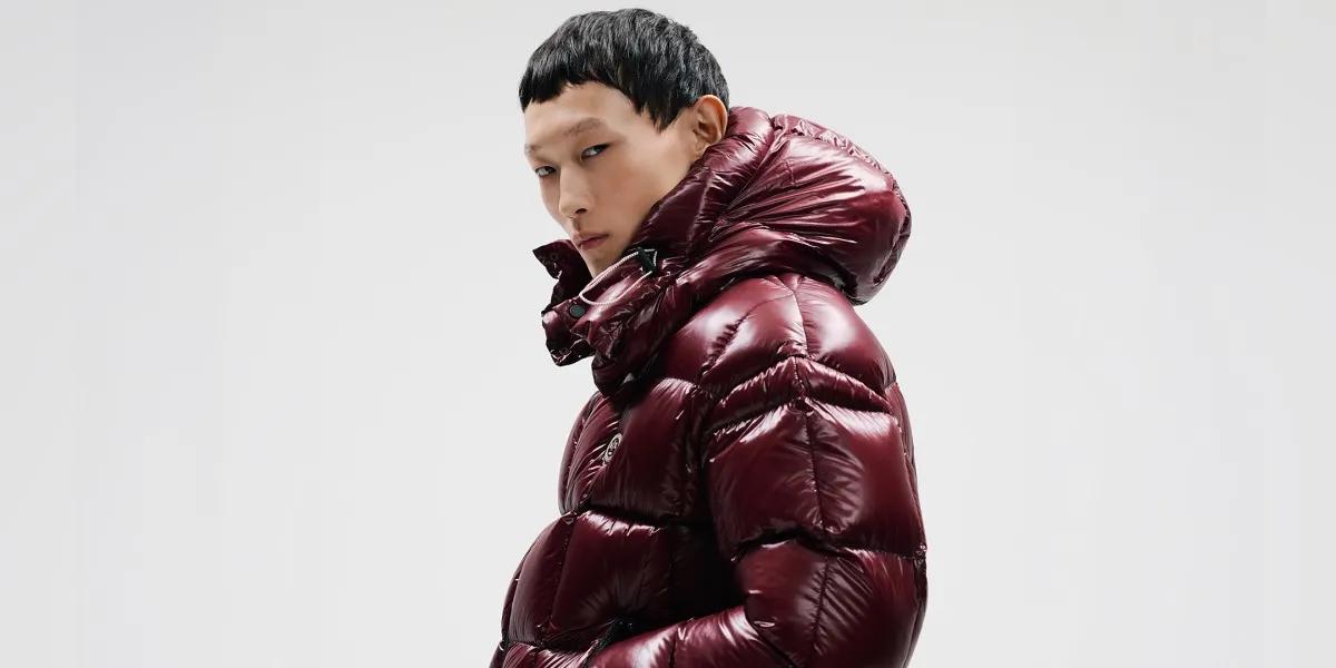 Un homme portant une doudoune à capuche burgundy brillante A|X Armani Exchange sur fond blanc.