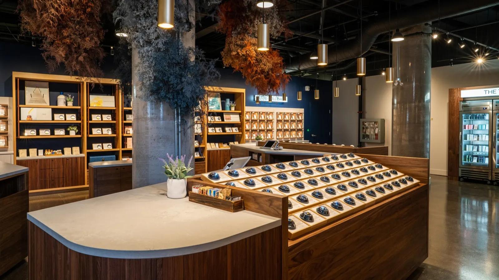 A modern retail store interior featuring wooden display counters and hanging dried floral arrangements.