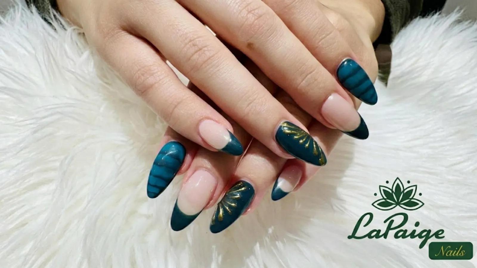 A close-up of manicure hands displaying teal and gold nail art resting on a white faux fur surface, with the LaPaige Nails logo in the corner.