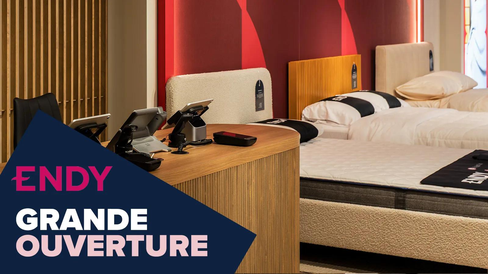 Une femme en pyjama assise les jambes croisées sur un matelas Endy dans un cadre de lit en bois.