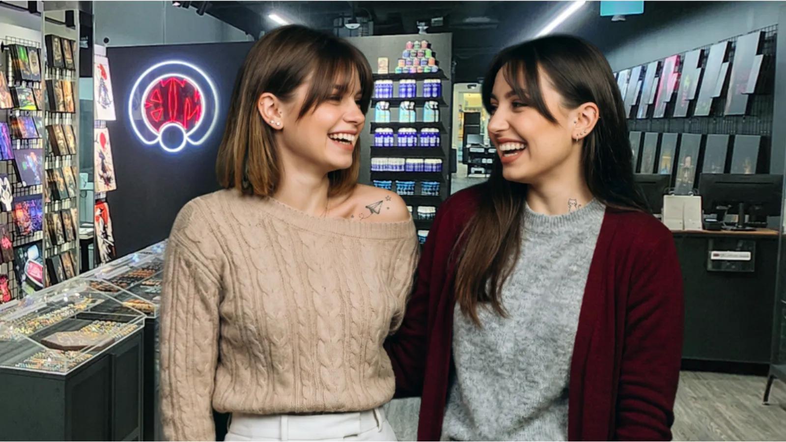 Two women smiling and laughing together inside a BodyMods tattoo and piercing studio.