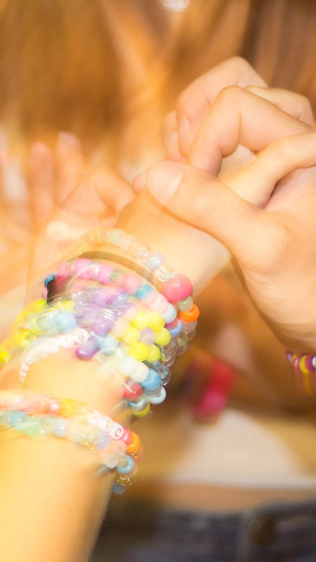 Two hands holding each other wearing bracelets