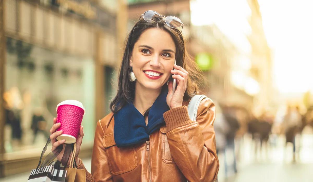 Woman window shopping with shopping bags and a coffee in her hand