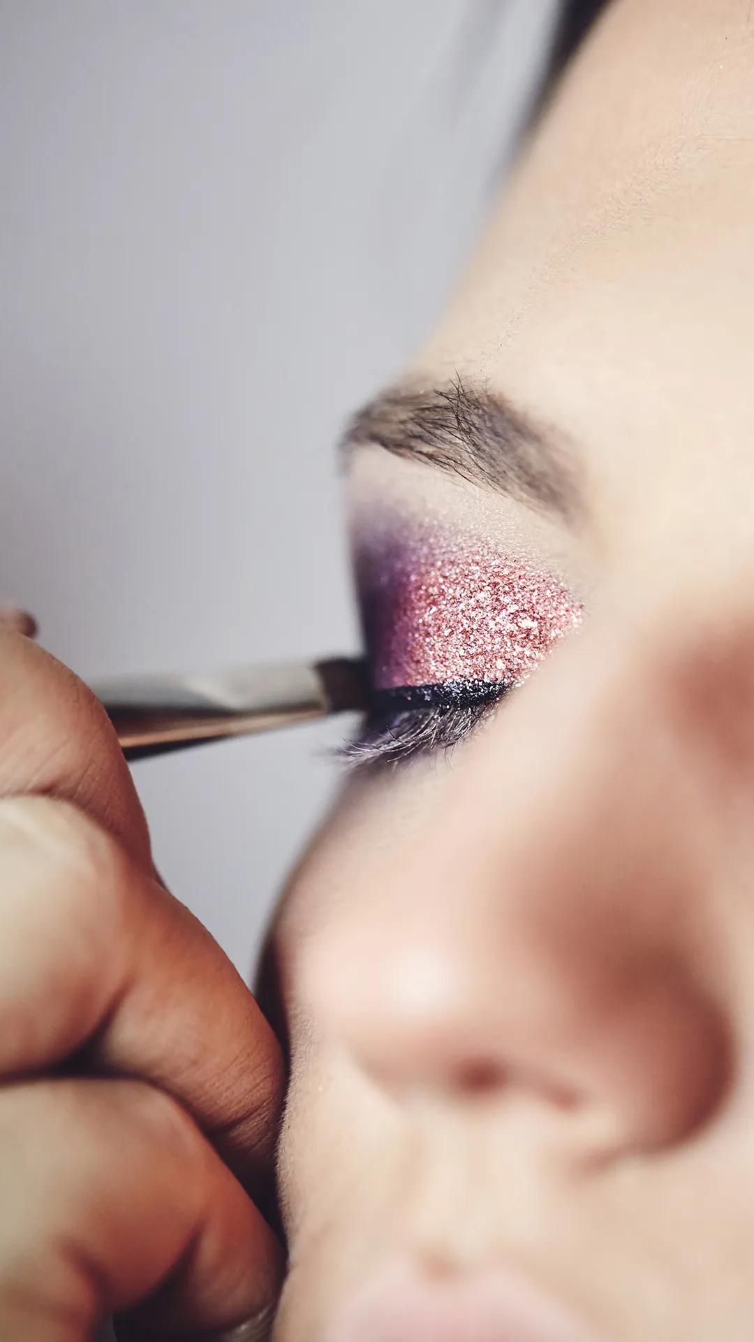 A close up of a women applying eye makeup